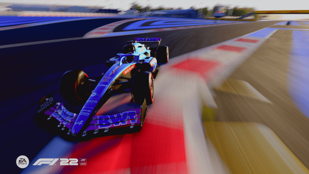 A close shot of an Alpine F1 car zooming towards the camera at sunset. It's front wheels are running over the inside kerb.