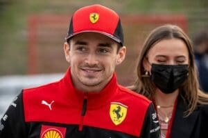 Charles Leclerc smiles while wearing his Ferrari hat and jacket.